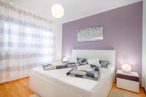 a bedroom with a white bed with pillows on it at Adria Sun Apartments in Vodice