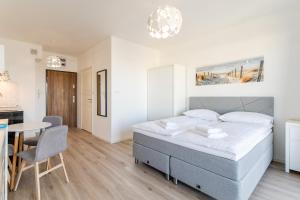 a bedroom with a bed and a table and a kitchen at Apartamenty Flamingo by Renters in Międzyzdroje