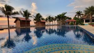a swimming pool in front of a house with palm trees at Serene Sands in Bang Lamung
