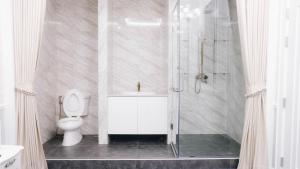 een witte badkamer met een douche en een toilet bij VARIMANTRA HOTEL in Nakhon Pathom