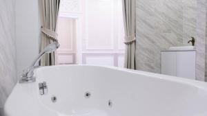 a white tub in a bathroom with a window at VARIMANTRA HOTEL in Nakhon Pathom