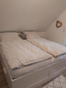 una cama blanca sentada en una habitación en Huus Utspann, en Tönning