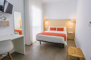 Habitación de hotel con cama con almohadas de color naranja en Hostal La Isla, en Carboneras