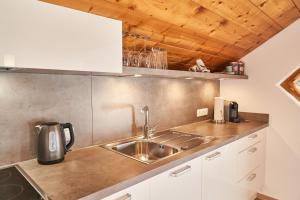 a kitchen with a stainless steel sink and wooden ceilings at Ferienhaus Tannenblick in Leutasch