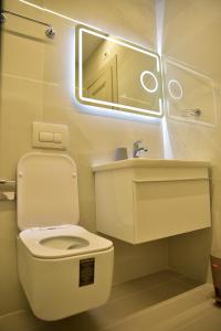 ein Badezimmer mit einem WC, einem Waschbecken und einem Spiegel in der Unterkunft The King Resort in Tirana
