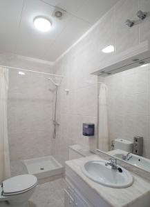a white bathroom with a sink and a toilet at Apartaments Can Xel in Santa Pau