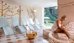 a woman sitting in a room with chairs at Alpwellhotel Burggräfler in Tesimo