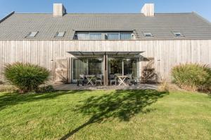 a house with a deck with a table and chairs at ParelDuyn in Oostkapelle