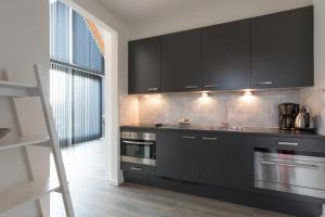 a kitchen with black cabinets and stainless steel appliances at ParelDuyn in Oostkapelle