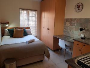 a bedroom with a bed and a desk and a sink at Kington Guest Suite in Pretoria
