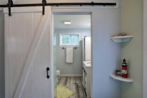 ein Bad mit einer Tür, die in ein Bad mit einem Waschbecken führt in der Unterkunft Shady Rest Studio 6 Mi to Ocean Isle Beach! in Shallotte