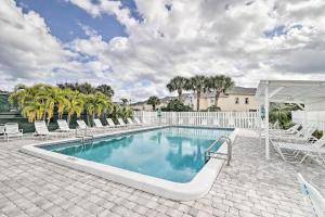 a swimming pool with chairs and a white fence at Jensen Beach Home with Pool Access Less Than 1 Mi to Beach! in Jensen Beach