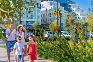a woman and two children walking down a sidewalk at Sealife Family Resort Hotel in Antalya