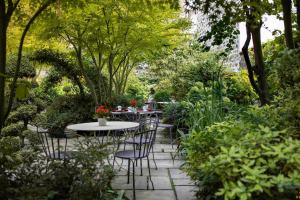 un patio avec des tables et des chaises dans un jardin dans l'établissement Hôtel Regent's Garden - Astotel, à Paris