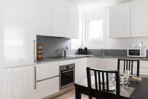 a kitchen with white cabinets and a table and chairs at Montarina Apartment by Quokka 360 - lovely accommodation a few minutes from the centre in Lugano