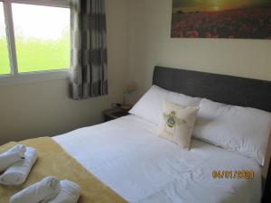 a bedroom with a bed with white sheets and a window at BUMBLEBEE in Dartmouth