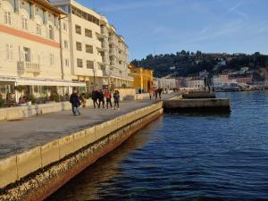 um grupo de pessoas andando em um passeio ao lado de uma massa de água em 3PAPIGE Apartment em Piran