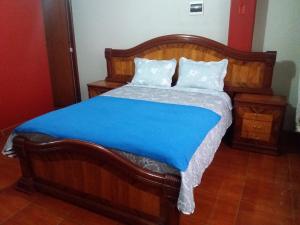 a bedroom with a wooden bed with a blue blanket at La Quilla House in Lima
