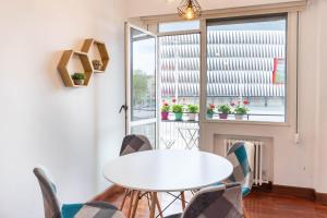 una mesa y sillas blancas en una habitación con ventana en Apartamento con vistas al Estadio San Mamés, en Bilbao