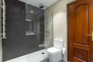 a bathroom with a toilet and a glass shower at Apartamento con vistas al Estadio San Mamés in Bilbao +24 photos