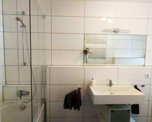 a white bathroom with a sink and a shower at Halbe Treppe in Potsdam