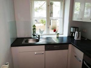 een keuken met een wastafel en een raam bij Halbe Treppe in Potsdam