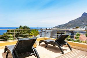two chairs on a balcony with a view of the ocean at Backup-Powered Camps Bay Beach Condo in Cape Town
