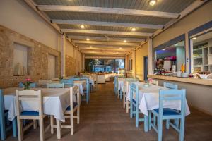 un restaurante con mesas blancas y sillas azules en Kordistos Hotel en Kefalos