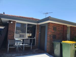 a brick house with a patio with a table and chairs at Airport budget room in Perth