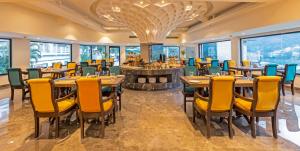 a restaurant with tables and chairs and windows at Lemon Tree Premier, Rishikesh in Rishīkesh