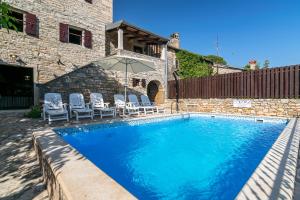 a swimming pool with chairs and an umbrella at Villa Maria in Oprtalj