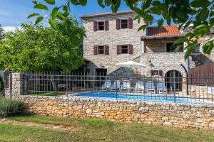 ein Steinhaus mit einem Zaun und einem Pool in der Unterkunft Villa Maria in Oprtalj