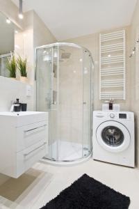 a bathroom with a shower and a washing machine at Love In Gdańsk AON Apartments in Gdańsk