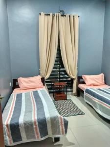 a room with two beds and a window with curtains at Shah Dangau Loqstaq Muslim Homestay in Kampong Sungai Mati