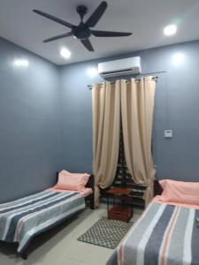 a bedroom with two beds and a ceiling fan at Shah Dangau Loqstaq Muslim Homestay in Kampong Sungai Mati
