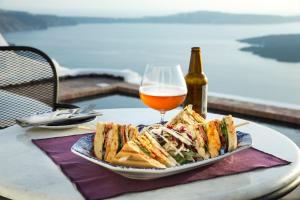 a plate of sandwiches and a glass of beer on a table at The Vasilicos in Imerovigli
