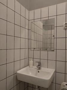 Baño blanco con lavabo y espejo en HoBar Hostel, en Budapest