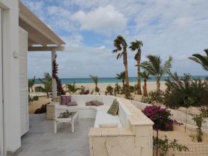 a patio with a white couch on the beach at Villa Alfredo Marchetti Nº13 A Suites on the Beach, Praia de Chaves, Boa Vista in Cabeçadas