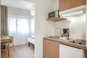 a small kitchen with a sink and a microwave at Appart'City Classic Annemasse Centre - Pays de Genève in Annemasse