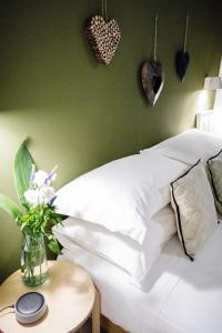 ein weißes Bett mit einer Blumenvase auf einem Tisch in der Unterkunft BB Casamatta in Neapel