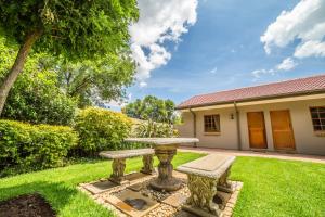 a garden with a stone table and benches at Beryl1 Guest House in Klerksdorp