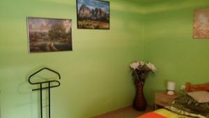 ein grünes Schlafzimmer mit einem Bett und einer Vase aus Blumen in der Unterkunft Zeg-zug Vendégház in Nemesdéd