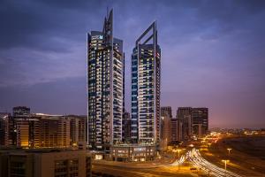 two tall buildings in a city at night at Millennium Place Barsha Heights Hotel in Dubai