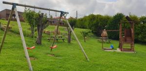 un parque infantil con columpios y una mesa de picnic en un campo en Bungalows Elma, en Suances