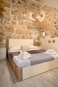 1 dormitorio con 1 cama en una pared de piedra en Jureca Guest House, en Siracusa
