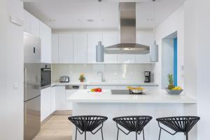 a kitchen with white cabinets and black stools at Villa Akrotiri in vlicha