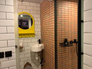 a bathroom with a sink and a yellow mirror at Wontonmeen in Hong Kong