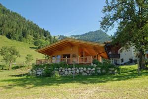 a log cabin with a porch and a stone wall at Der Ottenhof in Walchsee