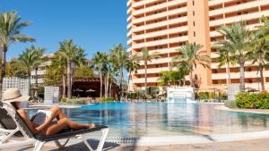 a woman laying in a chair next to a swimming pool at a resort at Hotel RH Ifach in Calpe
