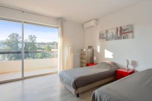 um quarto com 2 camas e uma grande janela em Appartement Panorama - Welkeys em Villeneuve-Loubet